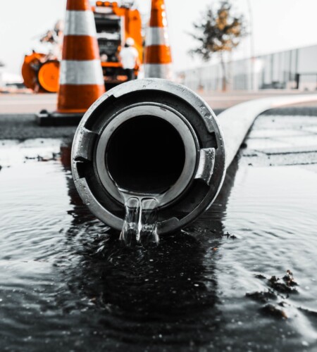 A selective closeup shot of a gray pipe with water coming out its hole